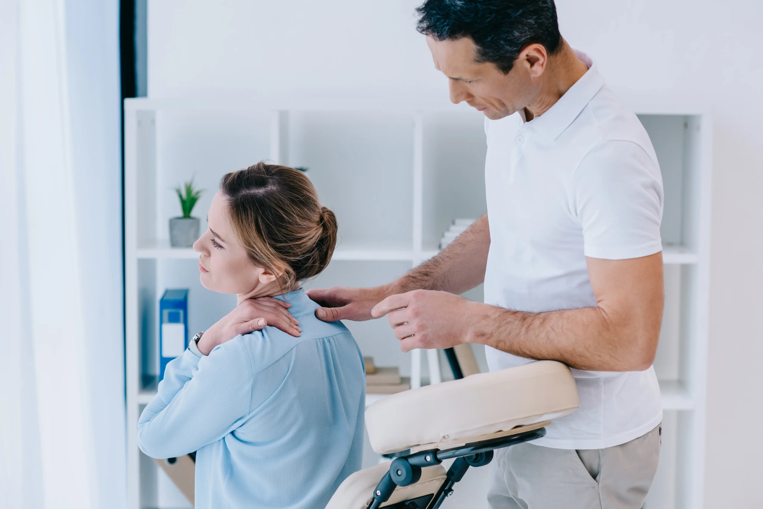 Chiropractor assessing a woman’s neck and upper back during a treatment session, representing Headache Chiropractor Calgary care.